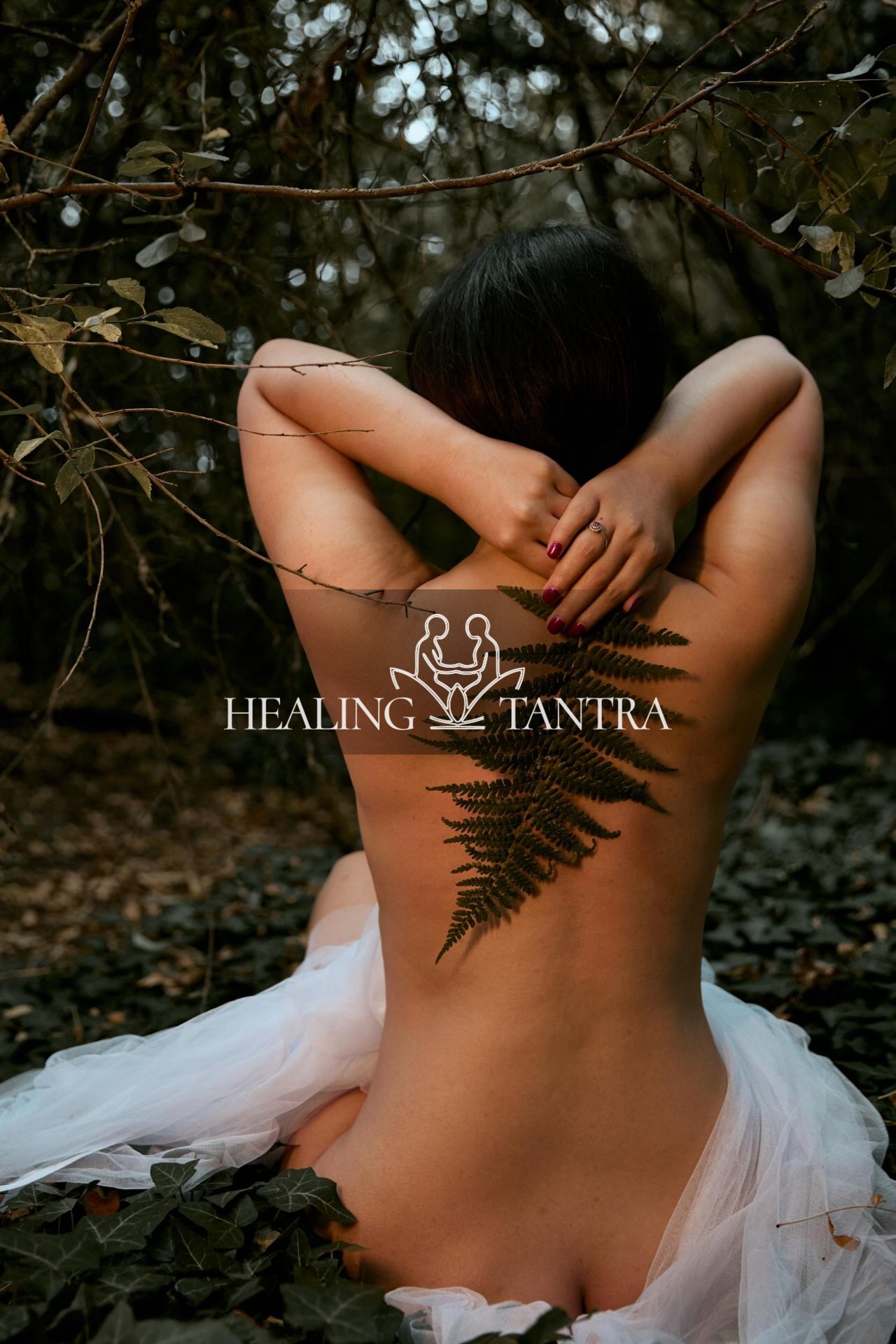 Bare back adorned with a single fern, seated in ivy
